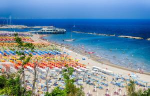 una spiaggia con molti ombrelloni e persone in acqua di Hotel Adler a Gabicce Mare