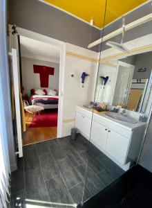Un baño con lavabo y espejo y un dormitorio. en Les Lamartine-chambres d'hôtes, en Le Mans