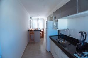 a kitchen with a black counter and a blue refrigerator at Monte das Oliveiras - Rede Tonziro in Arraial d'Ajuda