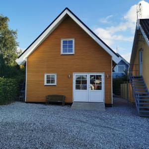 uma casa castanha com uma porta branca e uma escada em Samsø værelseudlejning em Tranebjerg