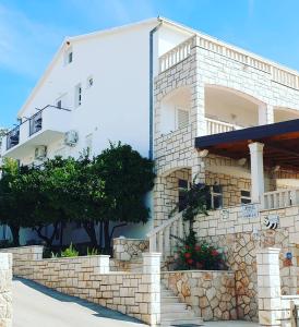 a white building with a stone wall and stairs at Pansion Braco in Zavala