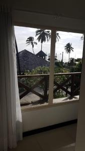 une fenêtre avec vue sur les palmiers et une clôture dans l'établissement ECO PARADISE _ CUMBUCO BOUTIQUE, à Cumbuco
