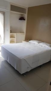 Cette chambre comprend un grand lit blanc et une fenêtre. dans l'établissement ECO PARADISE _ CUMBUCO BOUTIQUE, à Cumbuco