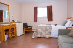 Una habitación de hotel con una cama, una mesa y un sofá. en Mayflower Inn, en Roddickton