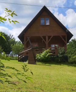 a log cabin on a grassy field with at PILGRIM domek gościnny w Gietrzwałdzie na Warmii in Gietrzwałd