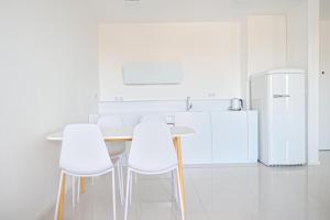 a kitchen with white chairs and a table and a refrigerator at City Center Aupark Apartment in Piešťany