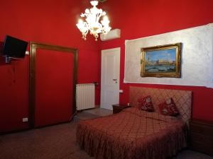 ein rotes Schlafzimmer mit einem Bett und einem Bild an der Wand in der Unterkunft Palazzo Lion Morosini - Check in presso Locanda Ai Santi Apostoli in Venedig