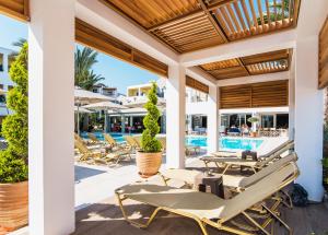 eine Terrasse mit Liegestühlen und einem Pool in der Unterkunft Dedalos Hotel in Malia