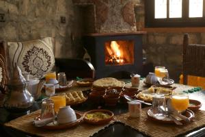 una mesa con comida y una chimenea en una habitación en Tonaroz House, en Imlil