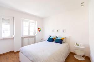 a white bedroom with a large bed with blue pillows at Ambassador River Shower Suites in Lisbon