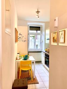 uma pequena cozinha com uma mesa e uma cadeira amarela em Charming City Apartment - by Nahuen Suites em Graz