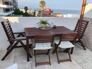 ein Holztisch und Stühle auf einem Balkon in der Unterkunft El Cortijuelo. Magnificent triplex terraced house with rooftop of 18m2, overlooking the sea. Parking in Torremolinos