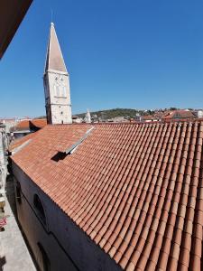 um edifício com um telhado vermelho com uma torre de relógio em Villa Sv. Petar em Trogir