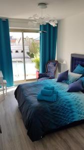 a bedroom with a bed with blue sheets and a large window at L'épopée de l'Avenue - Parking - Avenue de Champagne - Epernay in Épernay