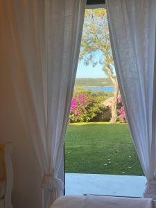 ポルト・チェルボにあるResidence Gli Oleandri 128 - Costa Smeralda - Porto Cervoの庭の景色を望む窓付きのベッドルーム1室