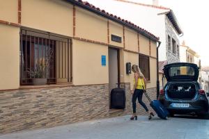 a woman walking down a street with her luggage next to a car at Panorama Suite in Ávila