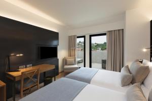 Habitación de hotel con 2 camas, escritorio y TV. en NEYA Porto Hotel, en Oporto