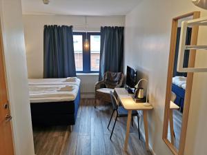 Habitación pequeña con cama y escritorio con silla. en Kils Hotell & Restaurang en Kil