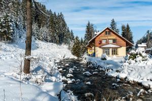 a log cabin in the snow next to a river at Penzion Jozef in Belá
