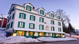 a large white building with green windows on a street at Auberge La Chocolatiere in North Hatley