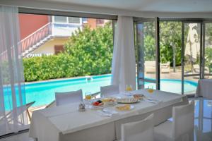 Biały stół z jedzeniem i winem oraz basen w obiekcie Hotel Levant w Sukošanie