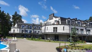 a large white building with a pool in front of it at Lesna Dreams Apartament in Pobierowo