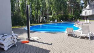 a swimming pool with white chairs and a group of people at Lesna Dreams Apartament in Pobierowo