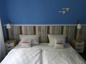 a bed with white sheets and pillows with a blue wall at Liebevoll hinterm Deich in Lehe