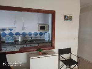 a kitchen with a black chair and a microwave at El Rincón de Umbria in Punta Umbría