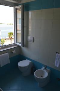 a bathroom with a toilet and a sink and a window at Hotel Merano in Grado