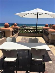 einen weißen Tisch und Stühle mit Sonnenschirm auf dem Balkon in der Unterkunft Lazorde bay duplex chalet, North coast in El-Alamein