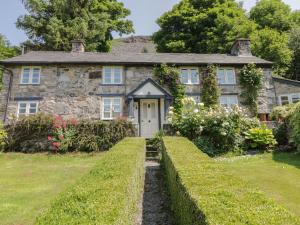 a stone house with a white door and some bushes at Haulfryn in Llangynog