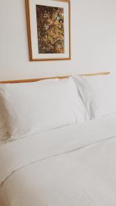 a bed with white sheets and a picture on the wall at Banbridge Inn in Charlottetown