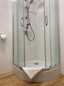 une douche avec une cabine de douche en verre et une serviette dans l'établissement LENA pokoje gościnne, à Międzyzdroje