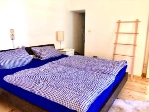 a bedroom with a bed with a blue and white comforter at Im Herzen von Ohlstadt und am Fusse des Heimgartens in Ohlstadt