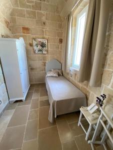 une petite pièce avec un lit et une fenêtre dans l'établissement Corte Fantasia, à Triggianello