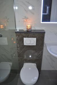 a bathroom with a toilet and a sink and a candle at Apartments REM-PIFRA in Novalja