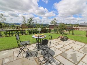 a patio with a table and chairs and a field at Woodland View in Saint Harmon