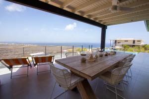 een houten tafel en stoelen op een balkon met uitzicht op de oceaan bij Villa Casawa in Kralendijk