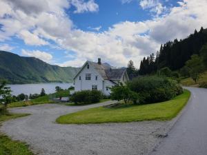 a house on the side of a road next to a lake at Irenegarden - Fjord view holiday home in Lauvstad