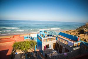 a blue building on the beach next to the ocean at Auberge Maison Diyani in Sidi Ifni