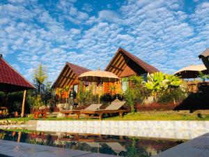 a house with a table and an umbrella next to a pool at Bukit Catu Bungalows in Kintamani