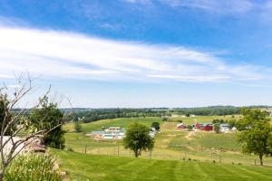 un campo verde con árboles y casas a lo lejos en Hillside Villa Ohio en Millersburg