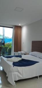 a bedroom with a large white bed and a window at Pousada Morada Azul in Porto De Galinhas