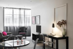 a living room with a table and chairs and a television at Punthill Apartment Hotel - Flinders Lane in Melbourne