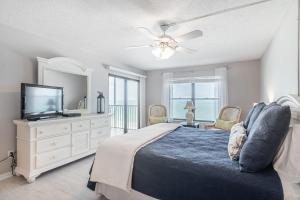 a bedroom with a bed with a television and a dresser at Reflections Gulf Front Condo With Ocean Views in Clearwater Beach