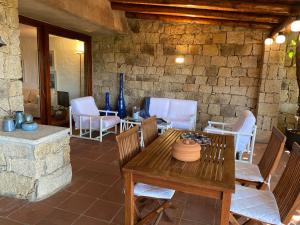 a patio with a table and chairs and a stone wall at Domus Olivarum - Costa Smeralda 6 guest, 3 room, 2 bathroom, 2 parking Wifi in Abbiadori