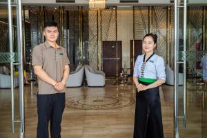 un hombre y una mujer parados frente a una puerta de cristal en Muong Thanh Grand Bai Chay, en Ha Long