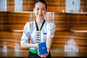 a woman is holding a book in a room at Muong Thanh Grand Bai Chay in Ha Long