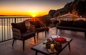 a balcony with chairs and a table with a sunset at Villa The View in Omiš